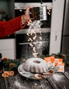A Person Dusting Powdered Sugar on a Cake