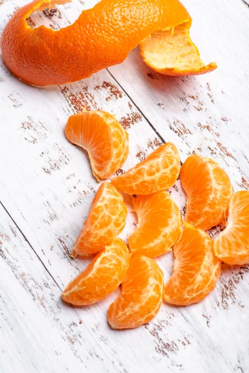 Free Vibrant orange slices and peel on a rustic white wooden table, perfect for food photography. Stock Photo