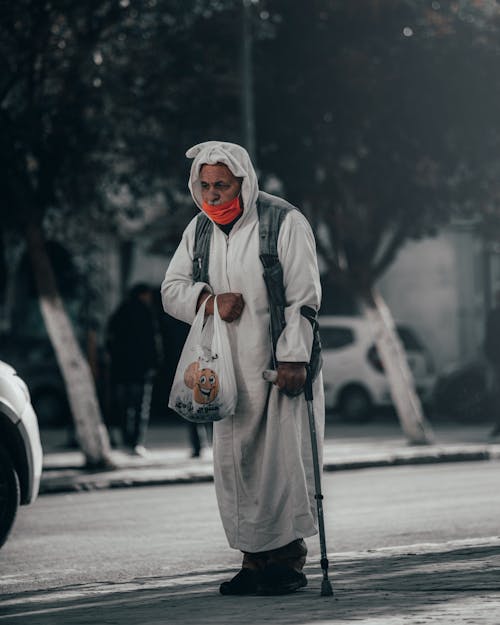 Man in White Traditional Clothes walking with a Cane 