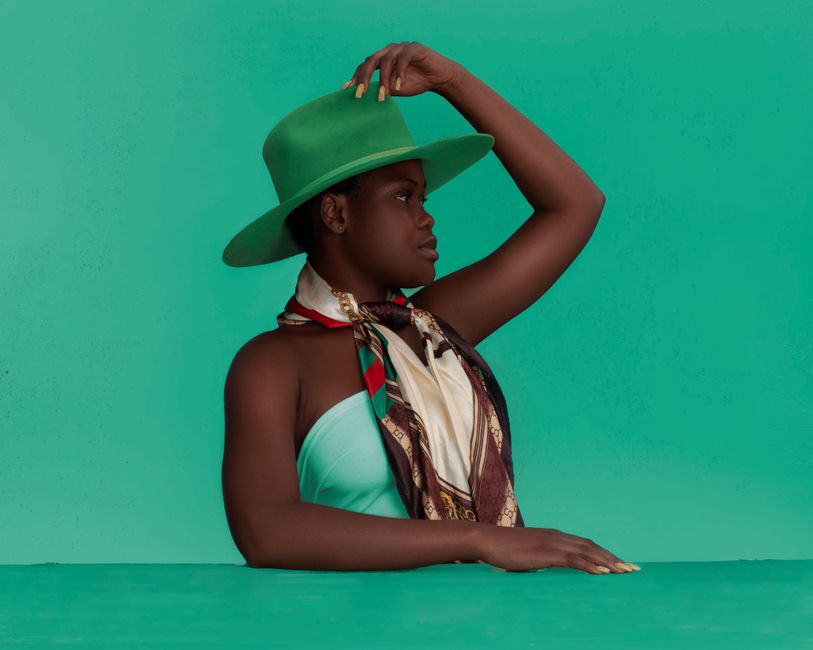 Side view of young African American female in green hat looking away