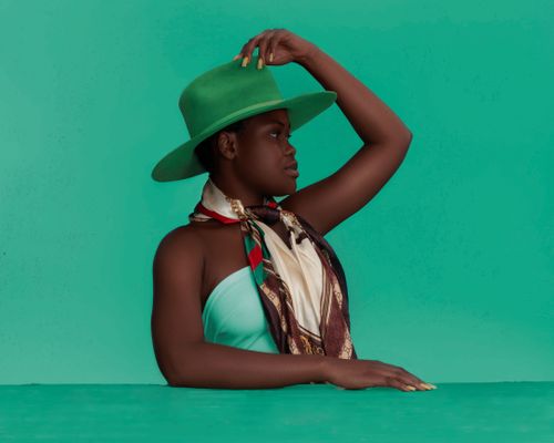 Free Side view of young African  American female in green hat looking away Stock Photo