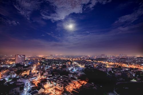 Free Breathtaking aerial view of Ho Chi Minh City at night with city lights and the moon illuminating the sky. Stock Photo