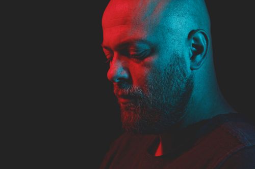 Free Intense moody portrait of a bald man highlighted by dramatic red and blue lighting. Stock Photo