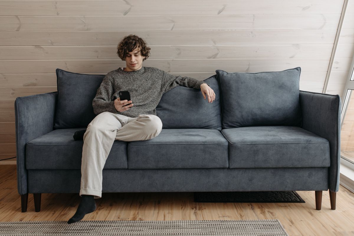 Young man relaxing on a sofa while checking his phone