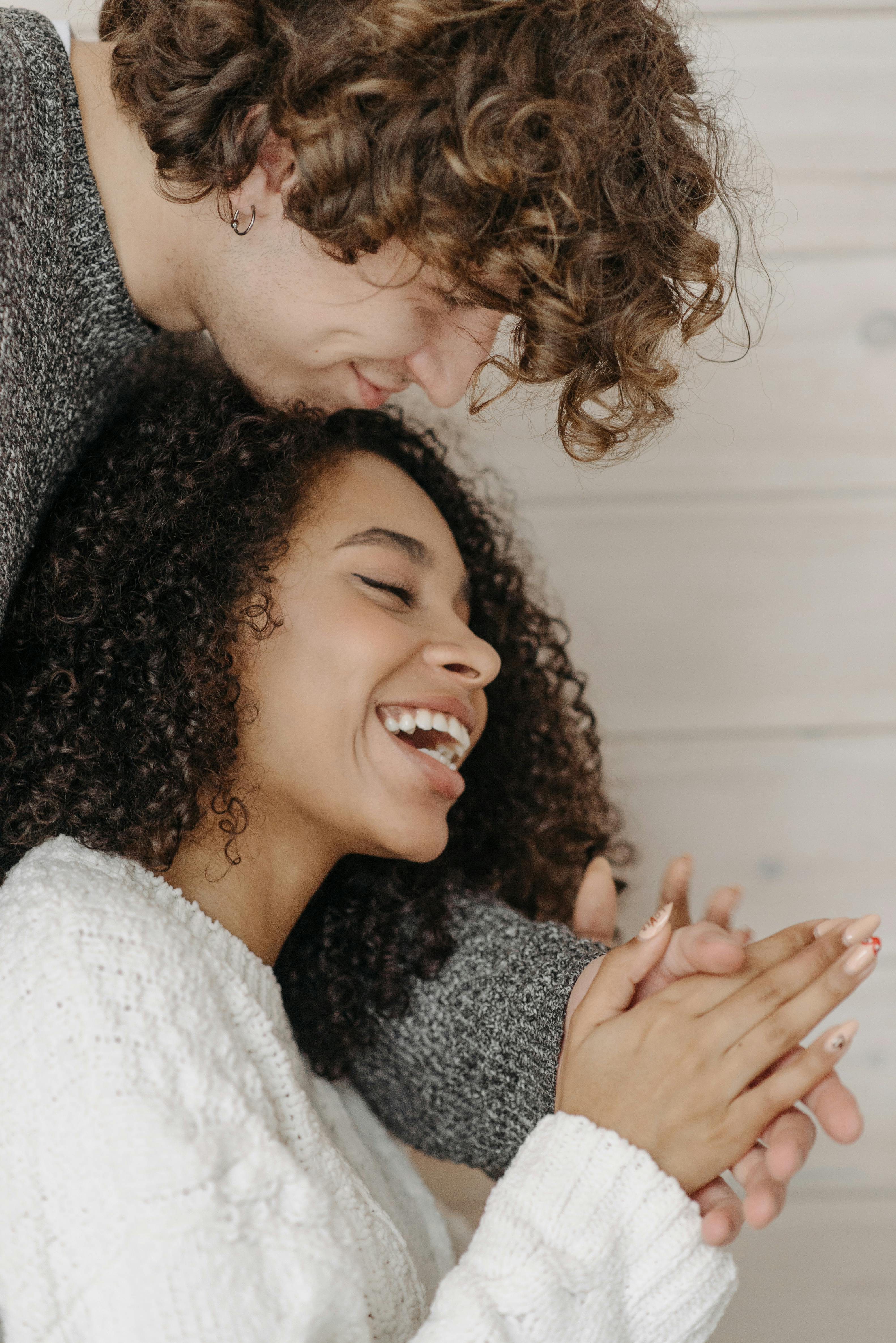 Happy couple embracing indoors, showcasing affection and joy in a warm setting.