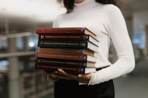 Free A Woman Holding a Stack of Books Stock Photo