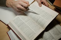 A Close-Up Shot of a Person Holding a Pen and an Open Book