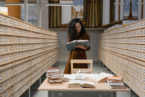 Free Woman reading a Book between Archive Drawers Stock Photo