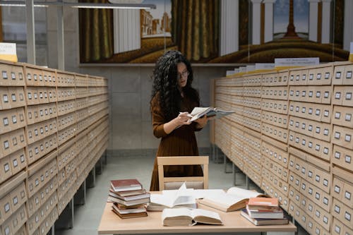 Woman reading a Book between Archive Drawers