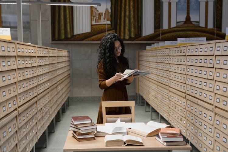 Woman Reading A Book Between Archive Drawers