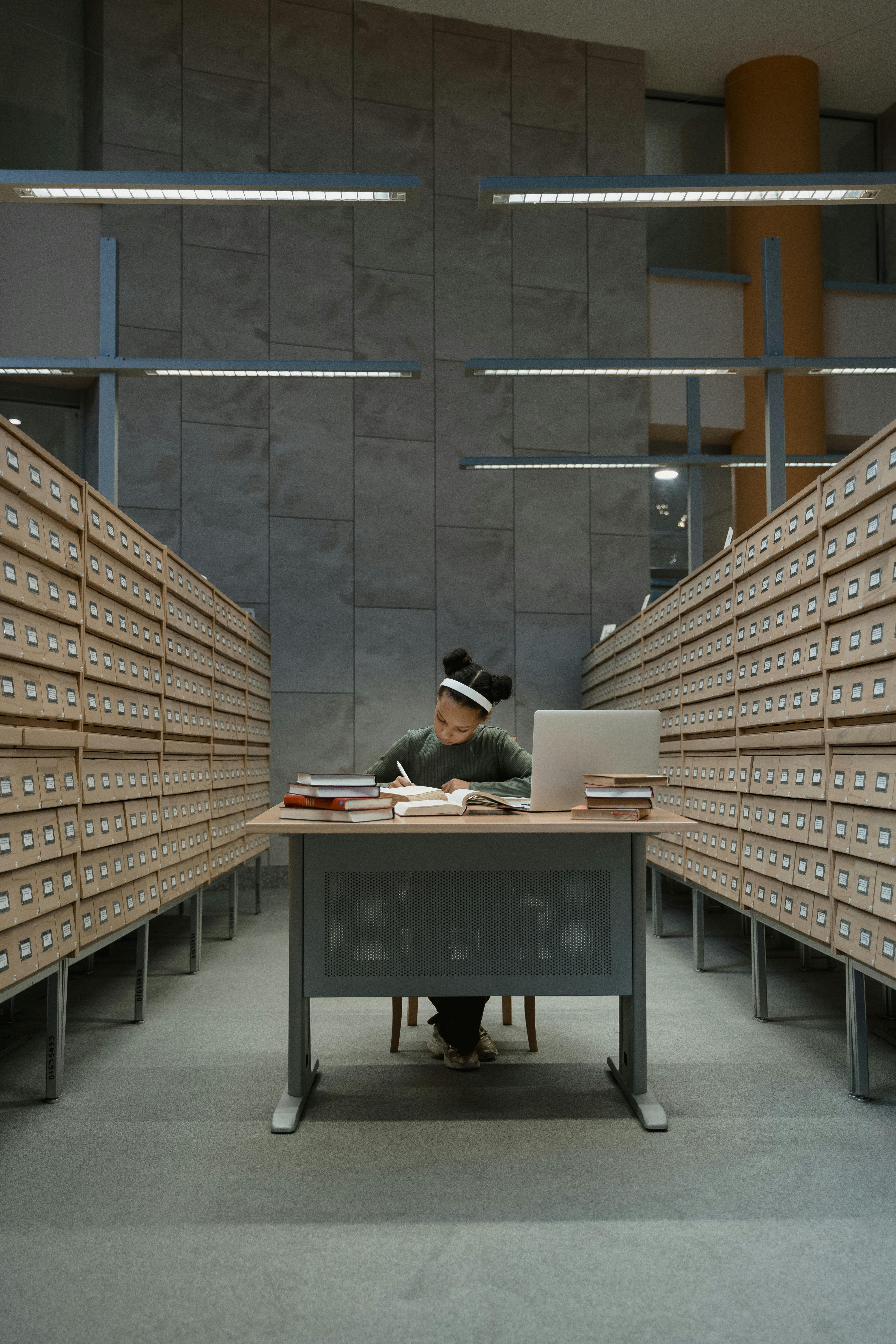 Free A person immersed in study at a library surrounded by card catalog drawers. Stock Photo
