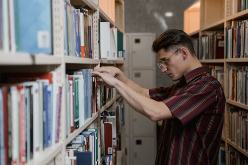 Male Student searching at Book Shelves