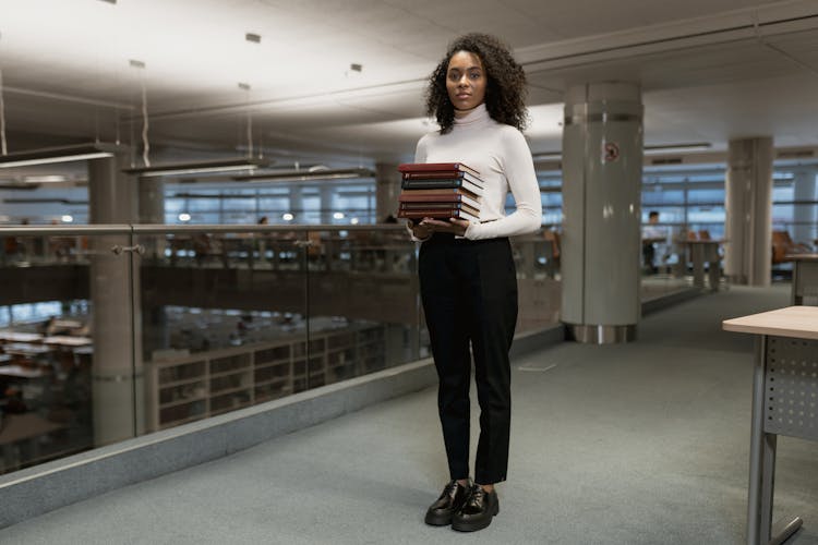 
A Woman Holding A Stack Of Books 