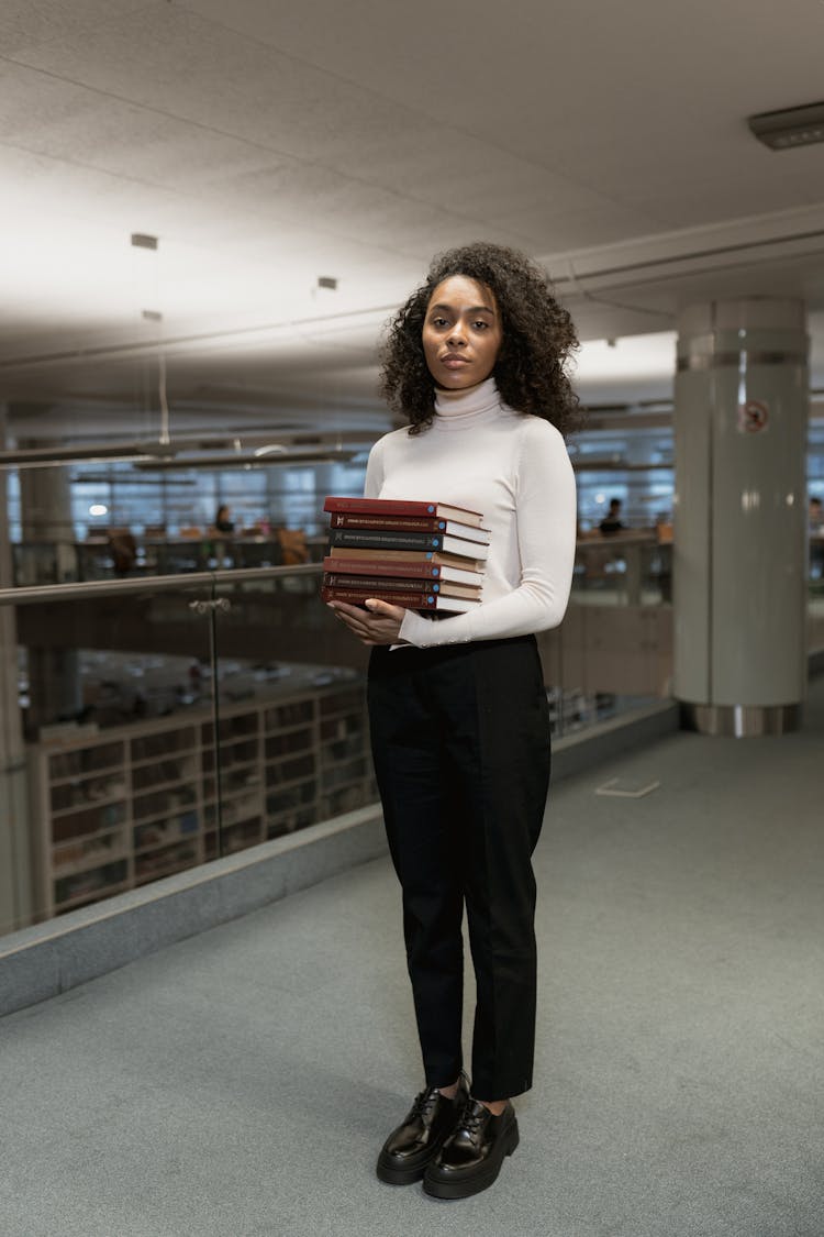 
A Woman Holding A Stack Of Books 