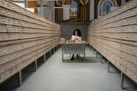 A Girl Sitting in Front of a Table Between Database Wooden Drawer