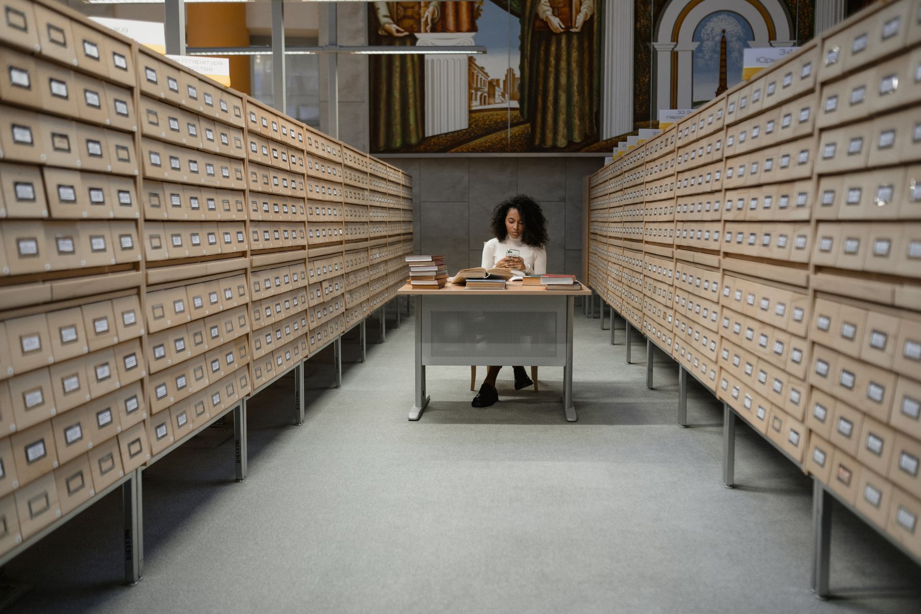 A reader seated between rows of archival catalogue drawers