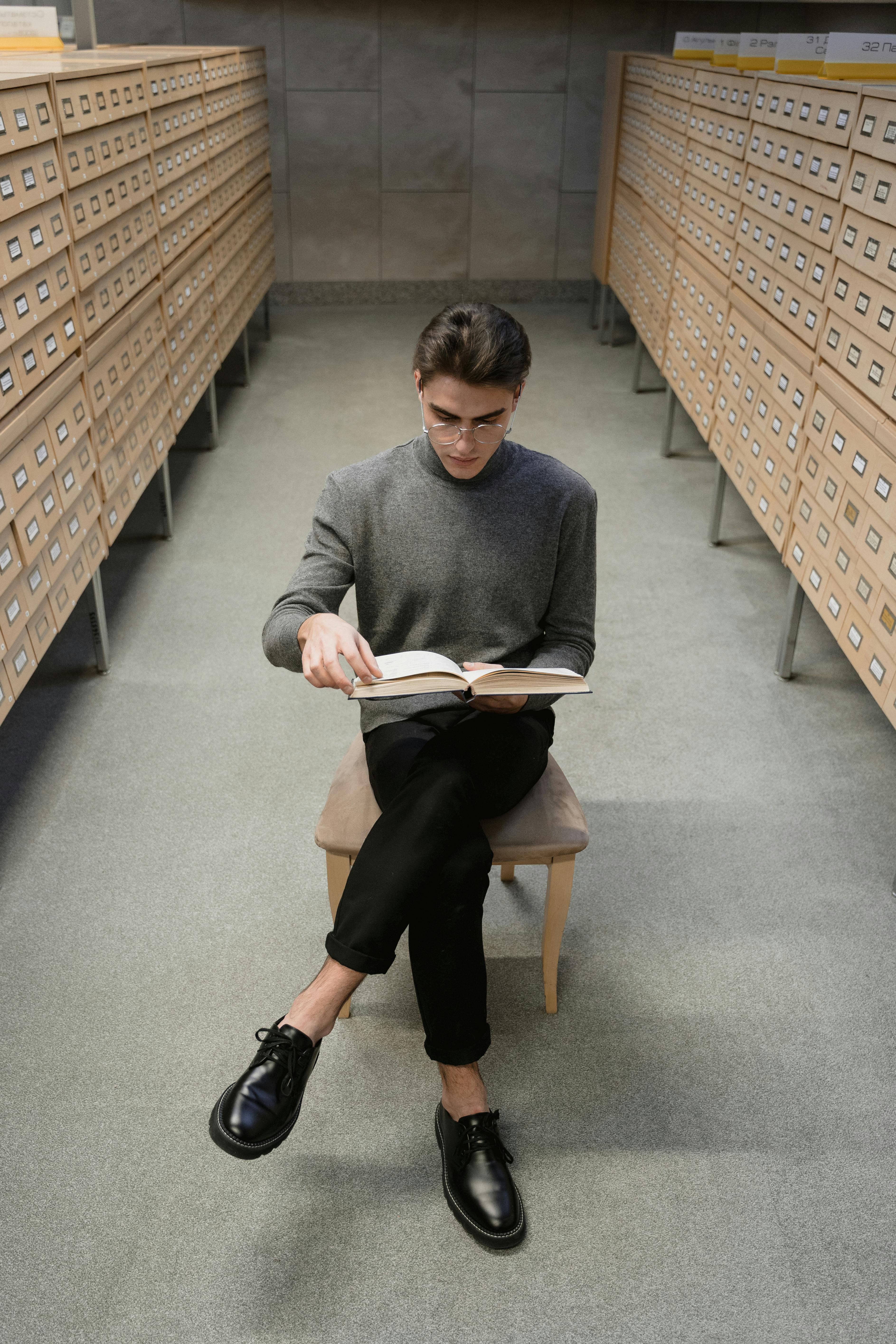 a young man reading a book in a library