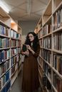 A Woman Holding a Book while Standing in a Library