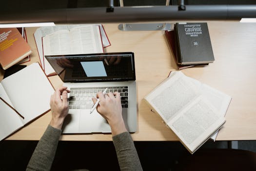 A student studies with a laptop and books, showcasing a learning environment.
