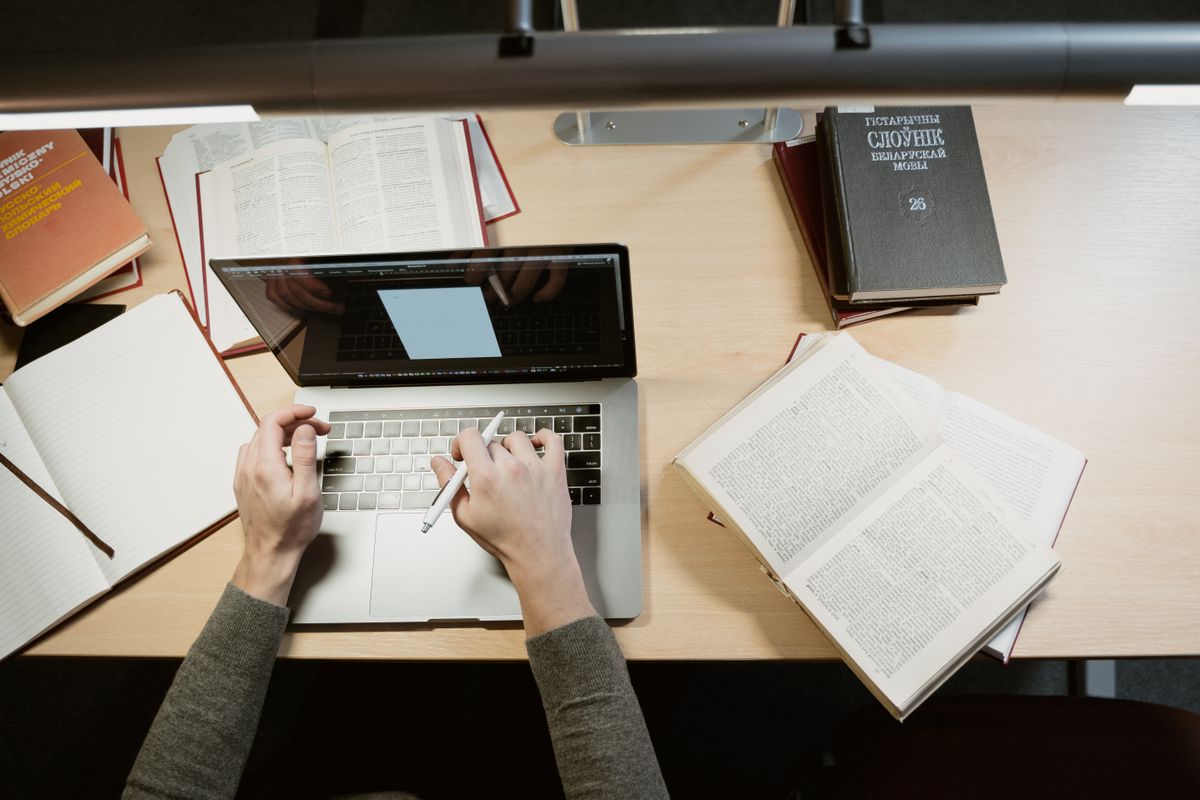 Student studying with laptop, books, and notes on a desk