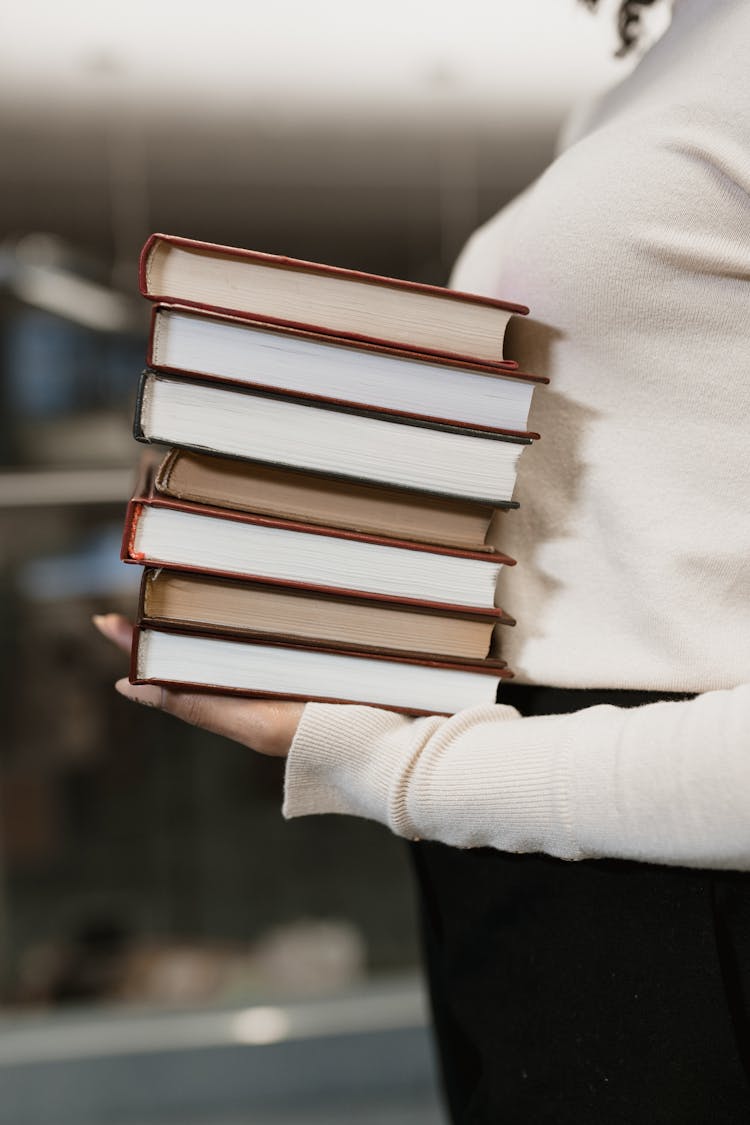 A Woman Carrying A Stack Of Books