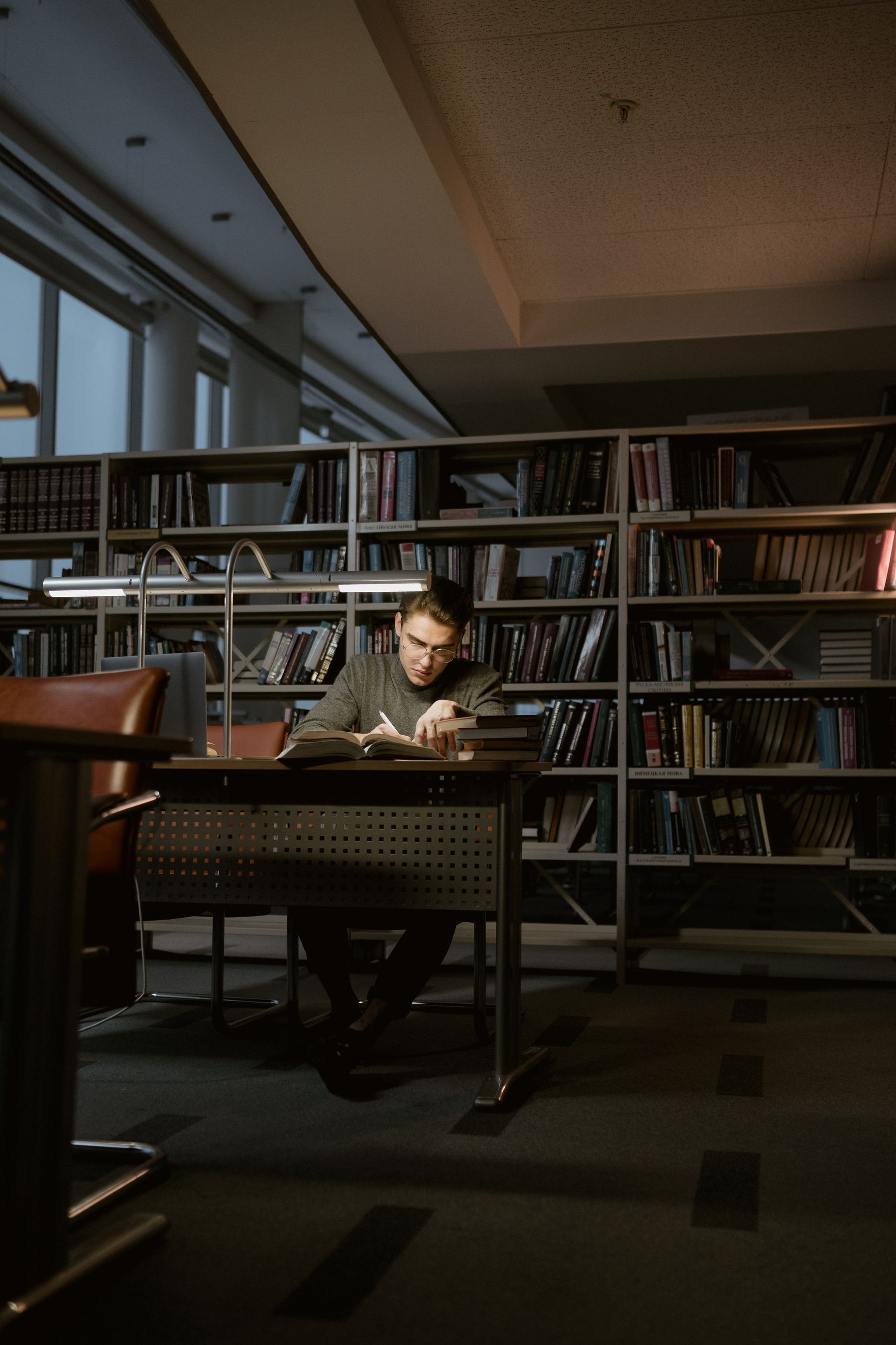 A man reading at a desk in a wood-shelved library