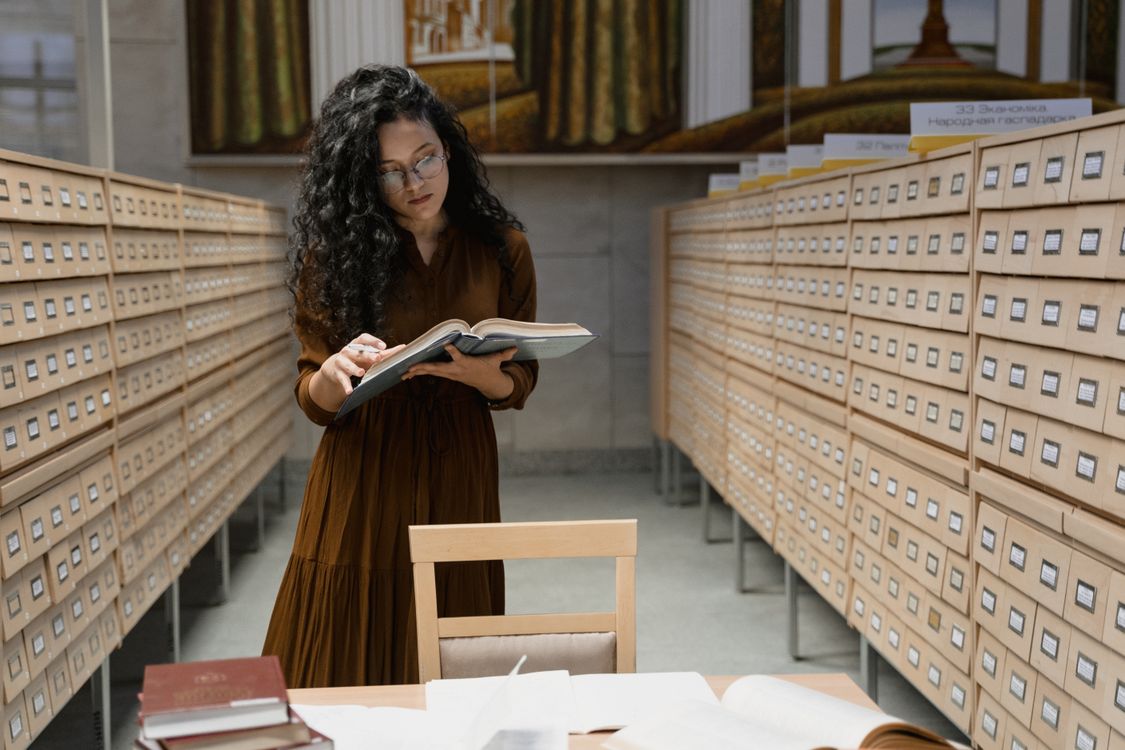 A Woman Reading a Book in the Library · Free Stock Photo