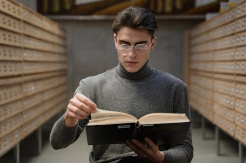 A Man in a Gray Sweater Reading a Book