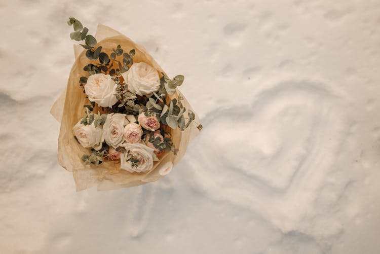 A Bouquet Of Roses On Snow Covered Ground With A Heart Drawing