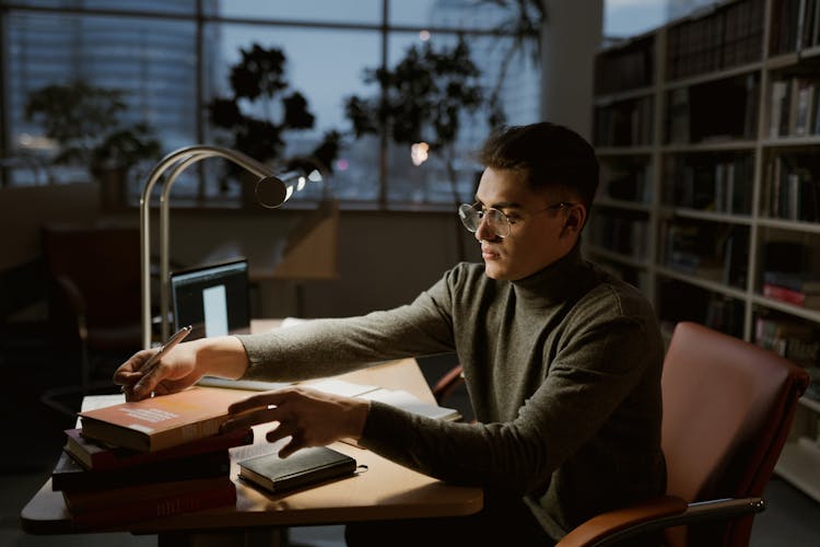 
A Man In A Turtleneck Sweater In A Library