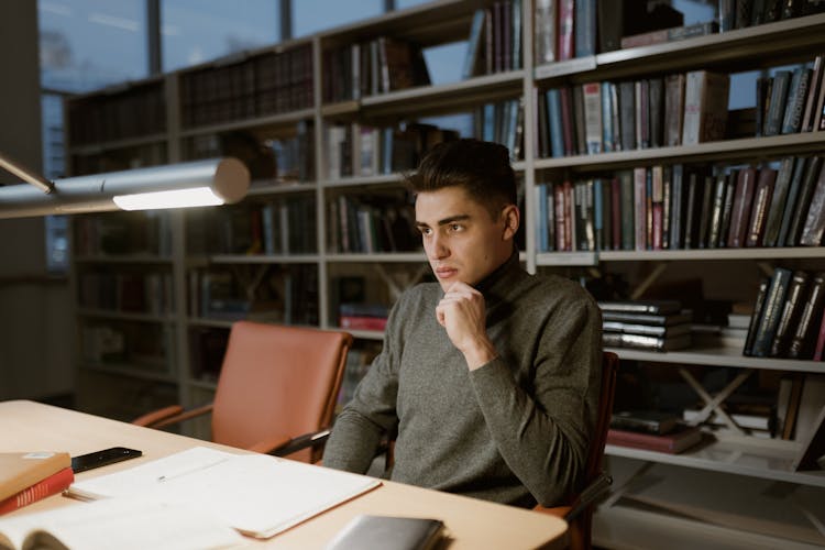 A Man In A Turtleneck Sweater In A Library