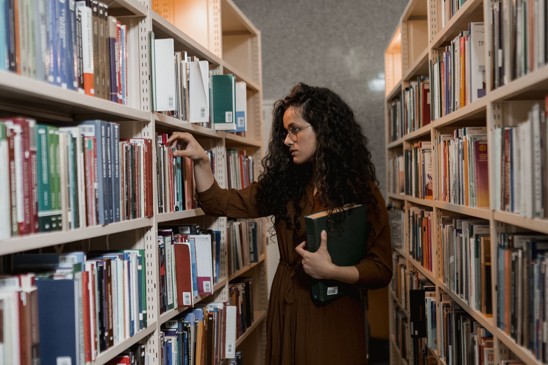 A Woman Choosing a Book on a Shelf