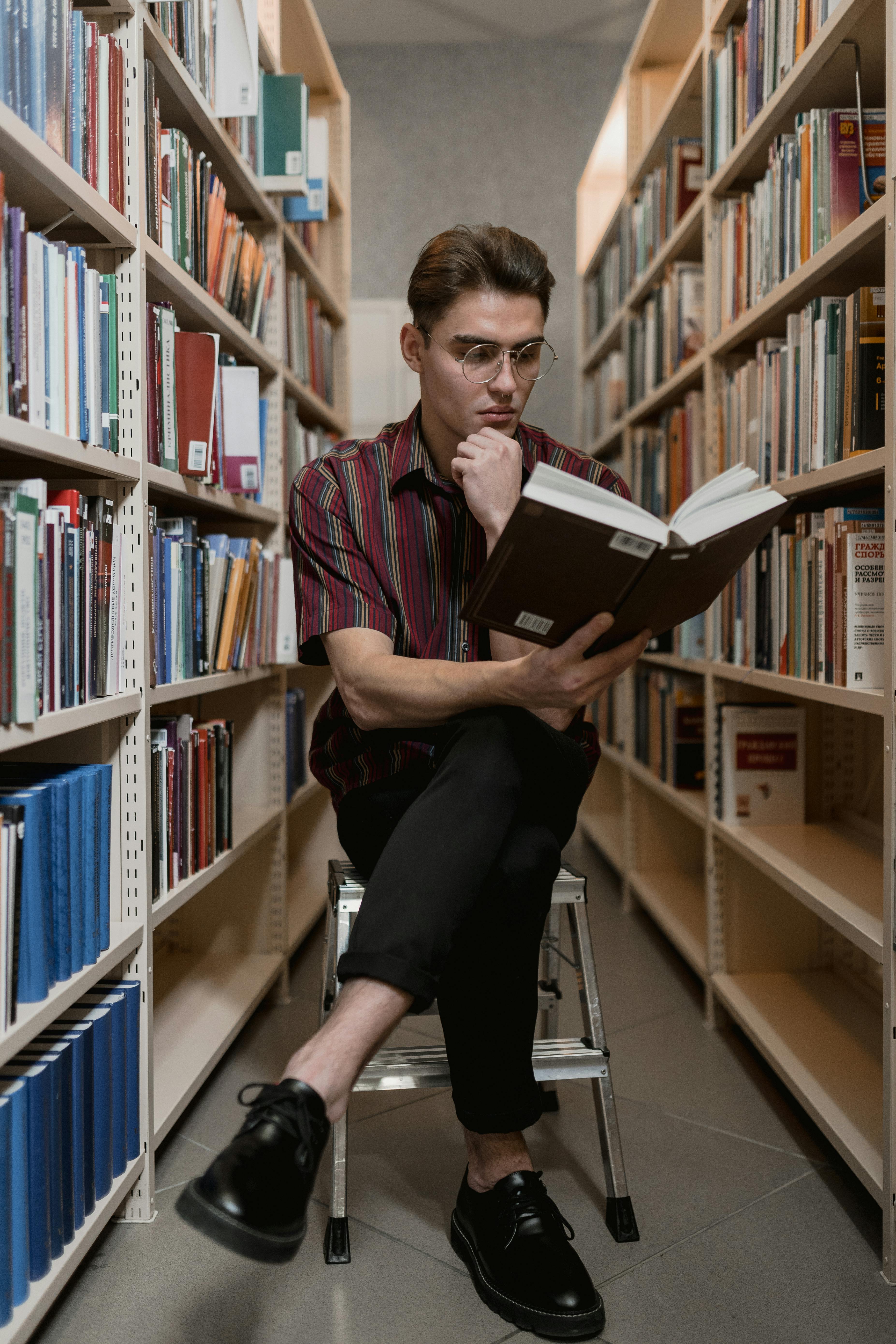 man sitting on a stool reading a book