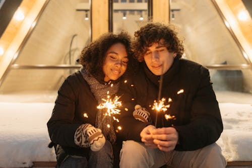 Cozy couple enjoying winter evening holding flashlers in a festive outdoor setting.