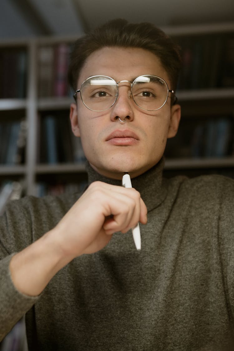 Close-up Photo Of A Pensive Male Student Holding A White Pen