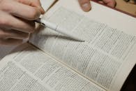 Close-Up Shot of a Person Pointing a Pen on a Book