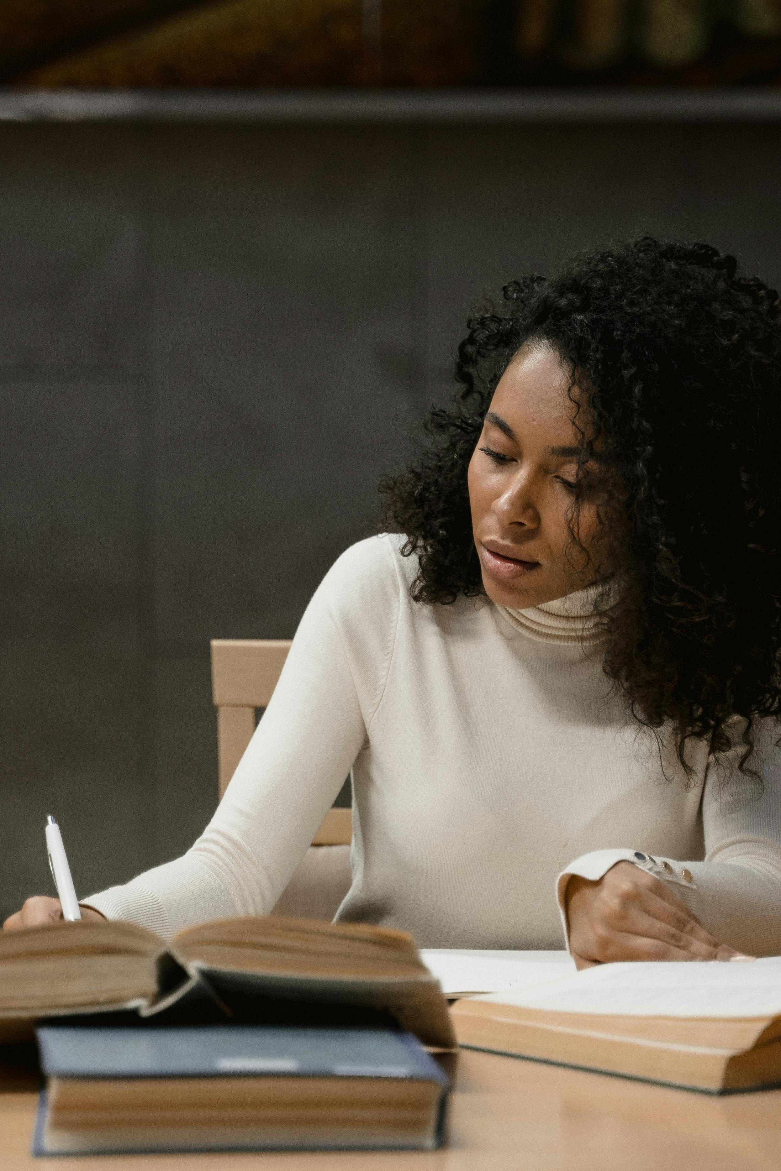 woman in white long sleeve shirt writing on white paper