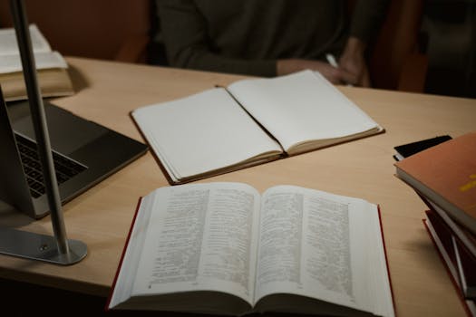 A warm, indoor study setup featuring open books and a laptop on a wooden desk, ideal for research and learning.