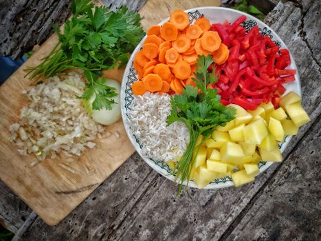 A colorful assortment of fresh vegetables and rice arranged on a rustic wooden table.