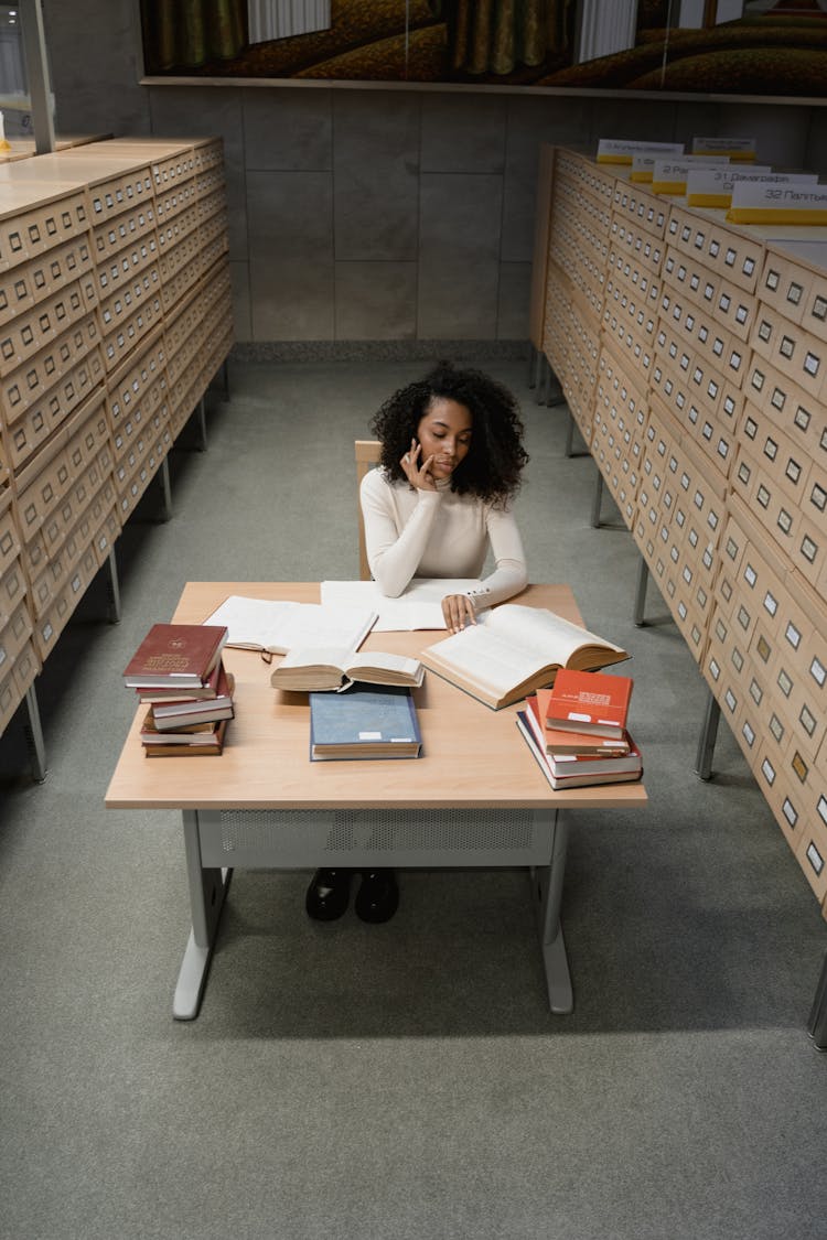 Woman Reading A Book Between Card Catalog In A Library