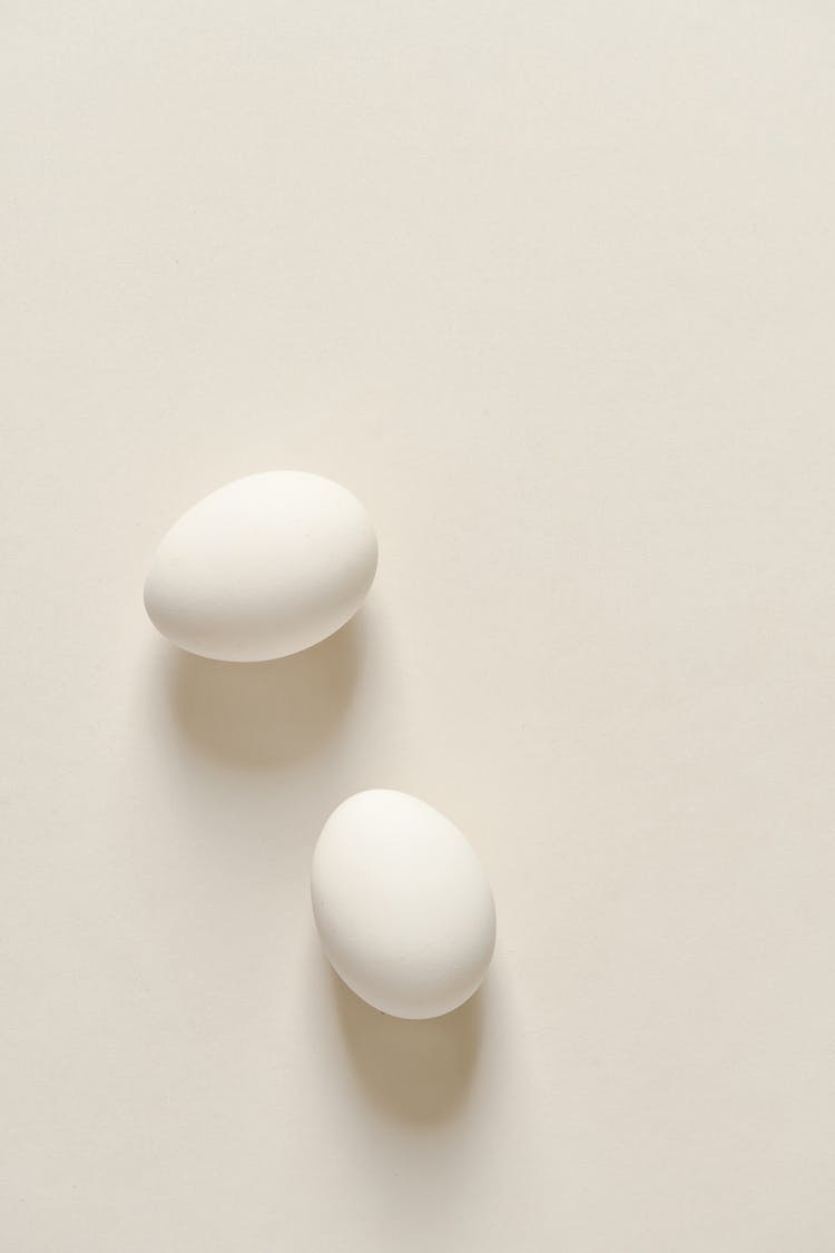 Two White Eggs On A White Surface