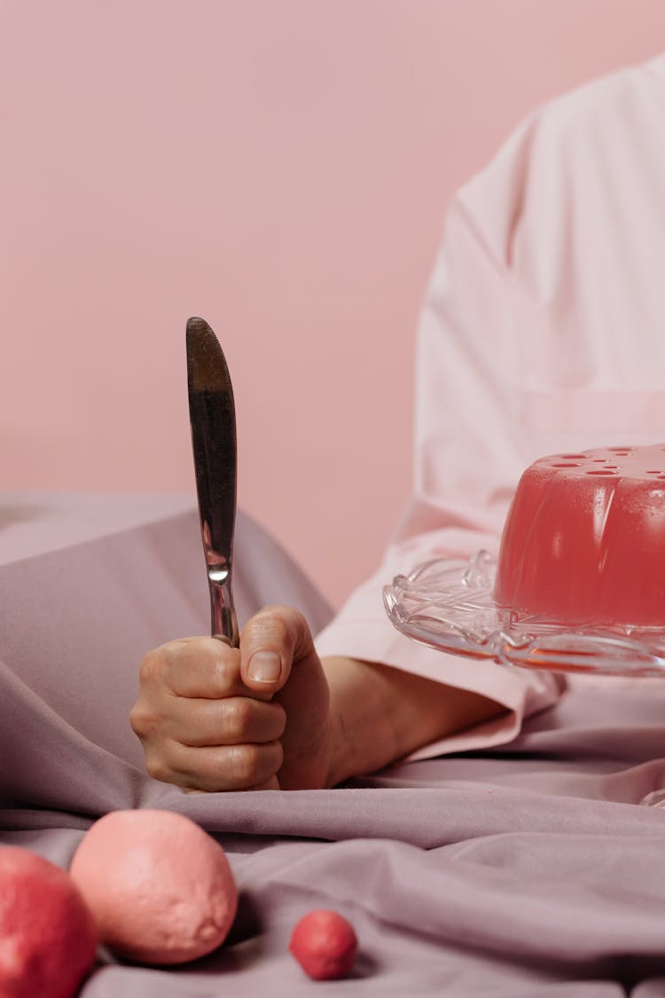 Hand Holding A Knife In Front Of Meal 