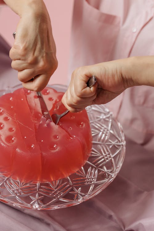 Close-up of Woman Cutting Pink Jelly with a Fork and Knife