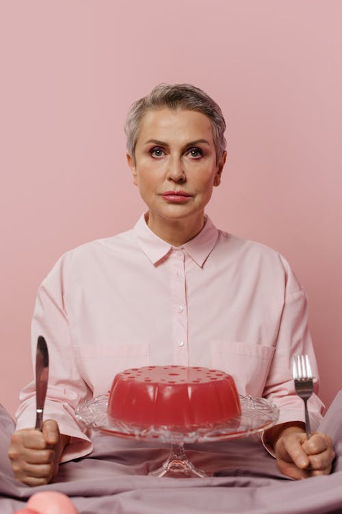 A Pink Jello Dessert in Front of a Woman in Pink Dress Shirt 