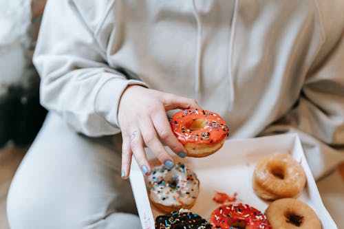 Free Crop faceless woman taking appetizing donut from box Stock Photo