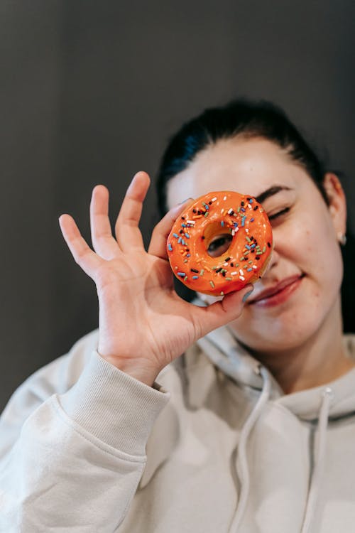 Content woman looking at camera through donut hole