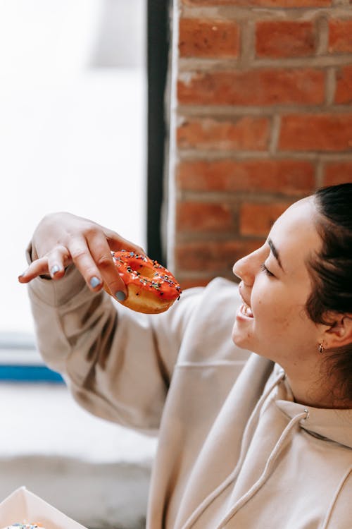 Crop happy woman enjoying delicious sweet donut