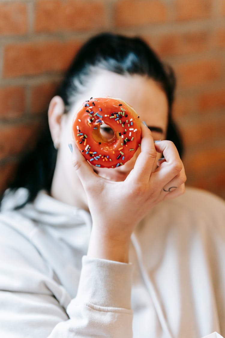 Smiling Woman Looking At Camera Through Delicious Donut Hole