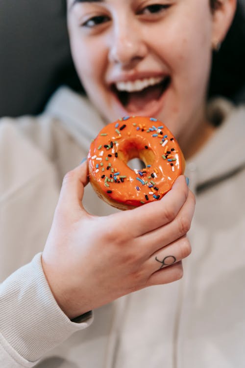 Crop joyful woman enjoying sweet donut