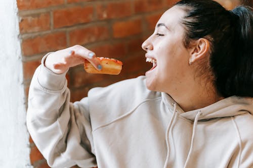 Crop excited woman eating fresh yummy donut